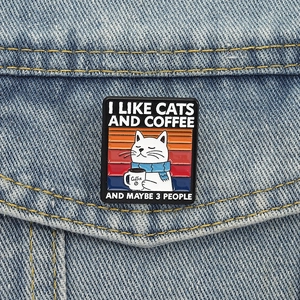Detail of funny cat enamel pin on denim jacket with 'I like cats and coffee' text
