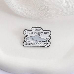 Broche créative en émail de requin gris avec texte humoristique en anglais sur fond blanc