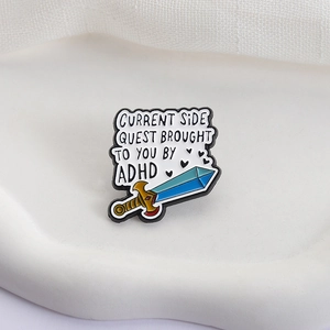 ADHD awareness enamel pin featuring sword design and humorous side quest text on white