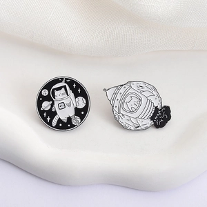 Space cat enamel pin set with astronaut cat and rocket landing on white fabric