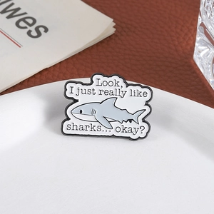 Funny shark enamel pin with 'Look I just really like sharks' text on white plate