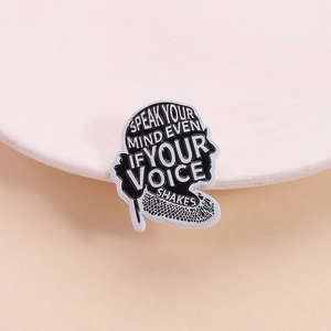 Inspirational enamel lapel pin with Speak Your Mind quote on white ceramic dish