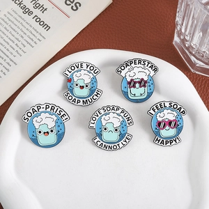 Set of five blue enamel soap pins with creative puns on a white ceramic plate