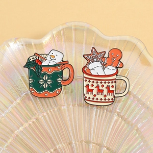 Christmas enamel pins featuring gingerbread man and snowman mugs on a shell tray