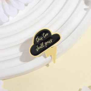Detail showing enamel cloud and lightning brooch with 'this too shall pass' engraving