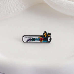Pin's émaillé Powered by ADHD avec icône de batterie colorée sur fond de tissu blanc