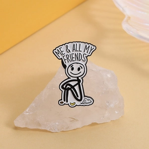 Close-up of stick figure enamel pin with Me and All My Friends text on white crystal