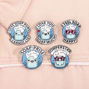 Lot de 5 épinglettes en émail motif savon avec jeux de mots sur fond en jean rose