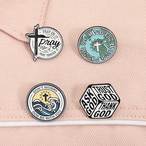 Close-up of four religious enamel pins with cross and inspirational quotes on pink denim