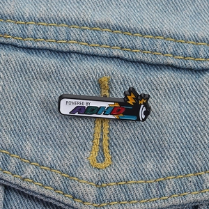 Badge créatif Powered by ADHD en émail sur une veste en jean bleu clair