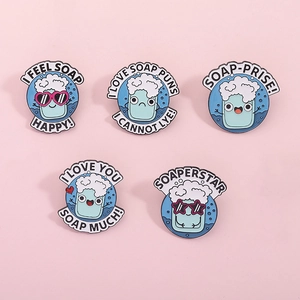 Cinq pin's en émail savon bleu avec jeux de mots créatifs sur fond rose doux