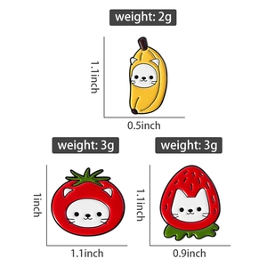 Detailed view of banana, tomato, and strawberry cat enamel pins with size and weight specs