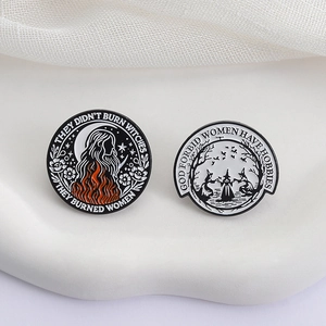 Two circular feminist witch enamel pins featuring artistic illustrations and slogans