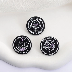 Macro view of three enamel feminist witch pins with Witches for Women's Rights text