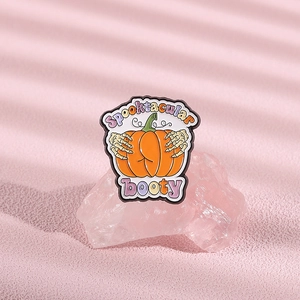 Détail d'une broche citrouille d'Halloween avec mains de squelette sur un cristal rose
