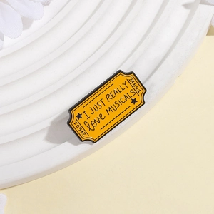 Détail du pin's en émail jaune au design de billet de théâtre musical avec cadre en métal noir