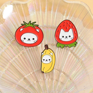 Vue détaillée des pins de chat en costumes de banane, fraise et tomate dans un plat en nacre