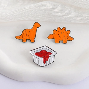 Set of 3 dinosaur chicken nugget enamel pins with tomato sauce cup on a white tray