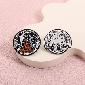 Vintage witch enamel pins with feminist quotes on a white geometric display stand