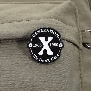 Gros plan détaillé d'un pin's émaillé noir et blanc Generation X sur tissu olive