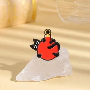 Detail of an enamel black cat brooch hugging a red ball on a white crystal stone