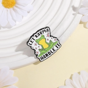Detail shot of meditation frog enamel pin with Let Karma Handle It text on white display