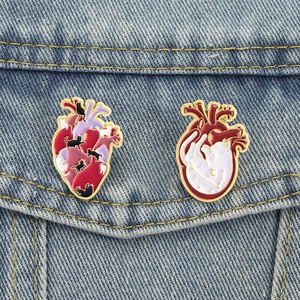 Détail de deux épingles en émail de chat et cœur sur une poche en jean
