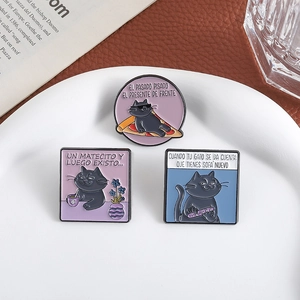 Trois pin's chat noir émaillés avec texte espagnol sur une assiette blanche élégante