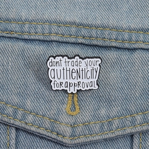 Épingle en émail avec citation sur l'authenticité sur une veste en jean bleue