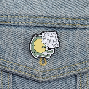 Spilla smaltata con rana divertente su denim e scritta If I am moody give me foody