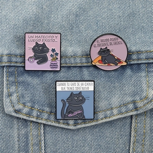 Three creative black cat enamel pins set on denim jacket featuring Spanish cat quotes