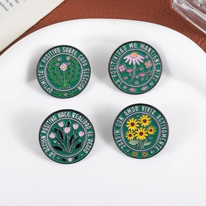 Artistic floral enamel pins set with Spanish motivational phrases on white plate