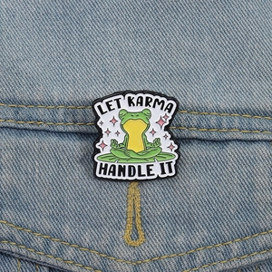 Funny meditation yoga frog enamel pin on denim with Let Karma Handle It text