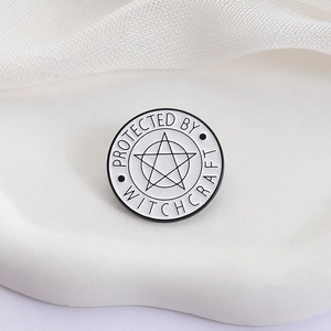 Macro detail of enamel star brooch with Protected by Witchcraft slogan on white background