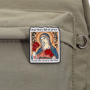 Detail of creative Virgin Mary pin with boxing gloves on khaki canvas background