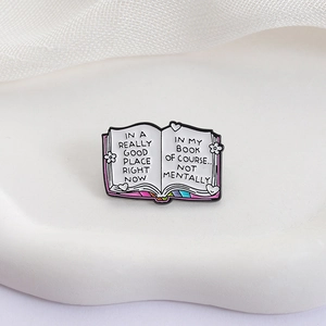 Creative enamel book pin with rainbow pages and inspirational quote on white tray