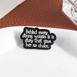 Broche en émail avec citation Behind every strong woman is a story sur une assiette blanche