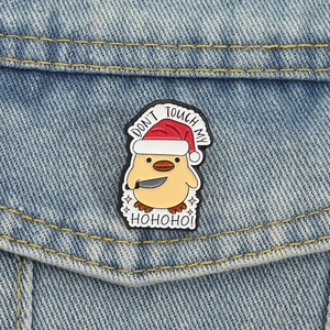 Cute Christmas duck enamel pin with Santa hat and knife on blue denim jacket