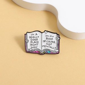 Detail of cartoon book enamel pin featuring humorous quotes and small floral patterns