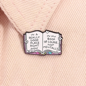 Detail of creative enamel book brooch pinned on pink denim featuring humorous text