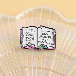 Colorful open book enamel pin with motivational quotes and hand-drawn floral patterns