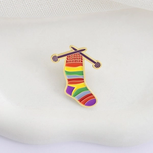 Colorful knitted sock enamel pin with knitting needles on white stone background