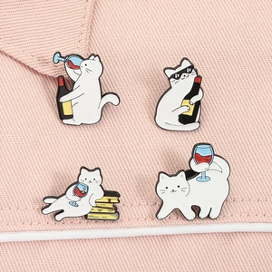 Detailansicht von vier lustigen weißen Katzen-Emaille-Pins mit Wein- und Buchmotiven