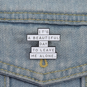 Pin's rectangulaire en émail avec texte sur la poche d'une veste en jean bleu