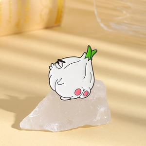 Close-up of a funny cartoon garlic enamel pin with a cheeky expression on a stone base