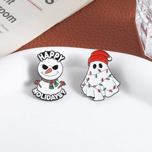 Enamel snowman and ghost holiday brooches set on white plate with festive Christmas theme