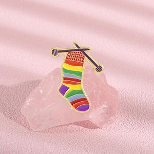 Macro shot of cartoon rainbow sock enamel pin on pink gemstone with gold-plated edges