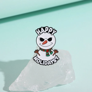 Detail of a Christmas snowman enamel pin with carrot nose and festive striped scarf