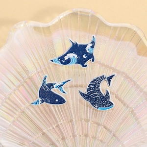 Three enamel ocean pins featuring whale sharks and rays in a glass shell container