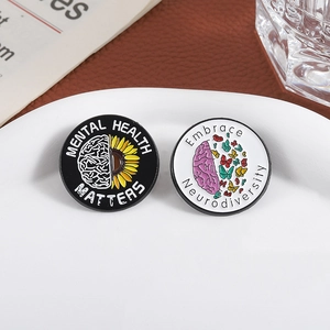 Broches émaillées Mental Health Matters et Neurodiversity présentées sur une assiette blanche